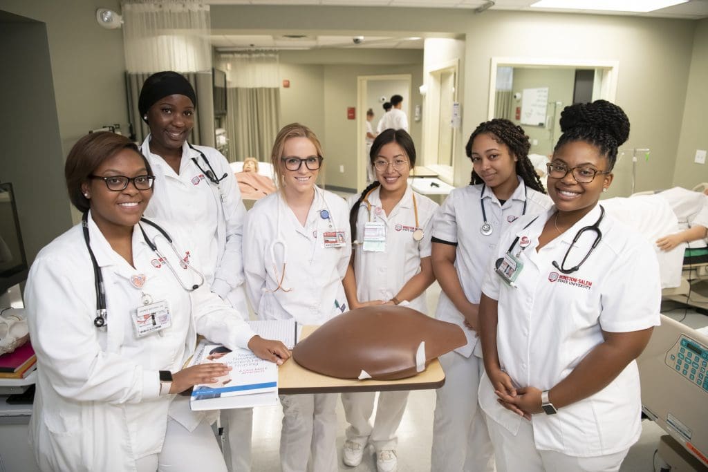 A group of nursing students gather around a model torso.