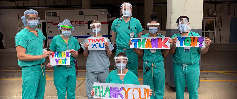 Medical professional hold up a thank you message to UNC Charlotte